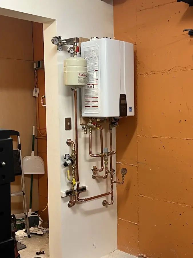 Plumbing technician inspecting water heater connections in Seven Corners